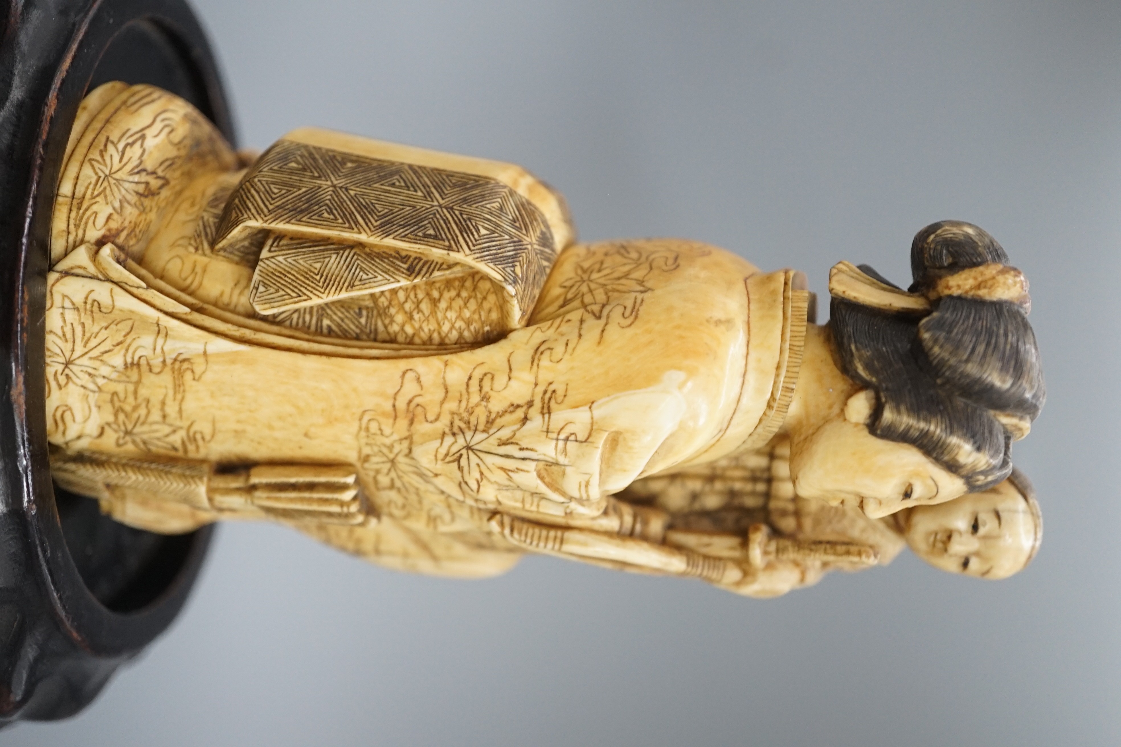 A Japanese ivory okimono of a lady holding a boy with a bow and arrow, Meiji period, restoration 12cm, wood stand